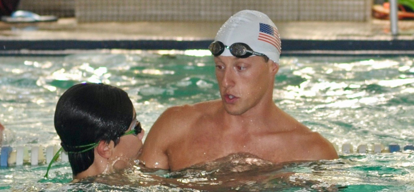 Olympic gold medalist Tyler McGill works with a participant at a Fitter and Faster swim clinic